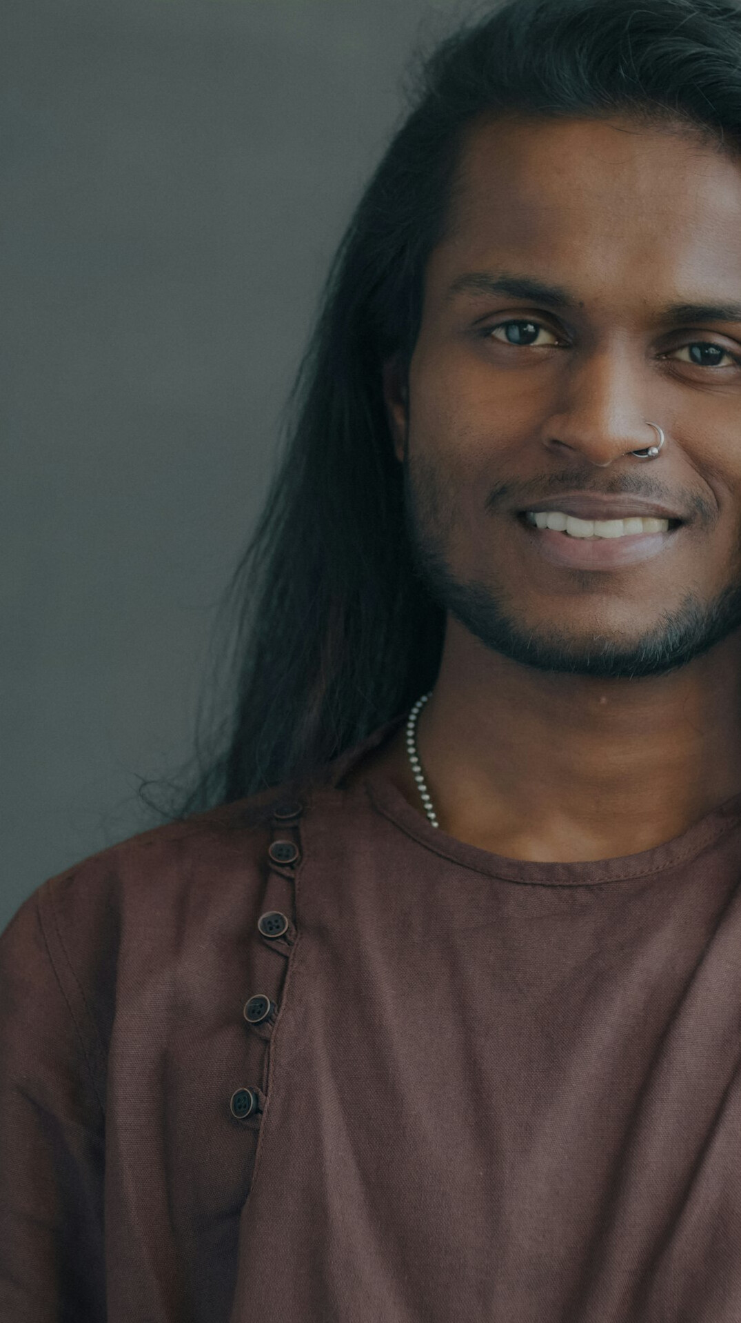 Brazilian man with short hair smiling in a studio portrait