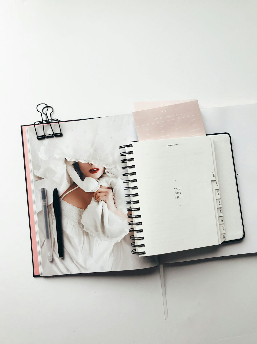 Top view of hands writing in a planner next to a laptop
